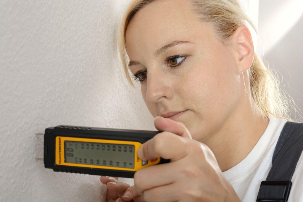 A woman holding a moisture meter testing moister of a home in Palm beach Florida